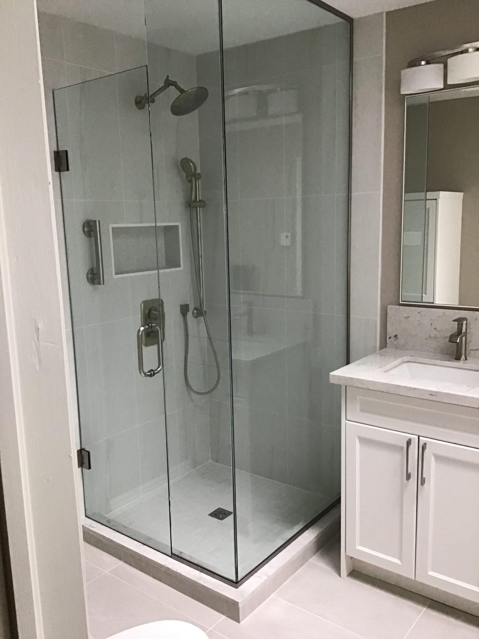 bathroom-renovation-london-ontario-donaldson.jpg Modern bathroom with a glass shower enclosure, rain showerhead, and white vanity with marble top and mirror.