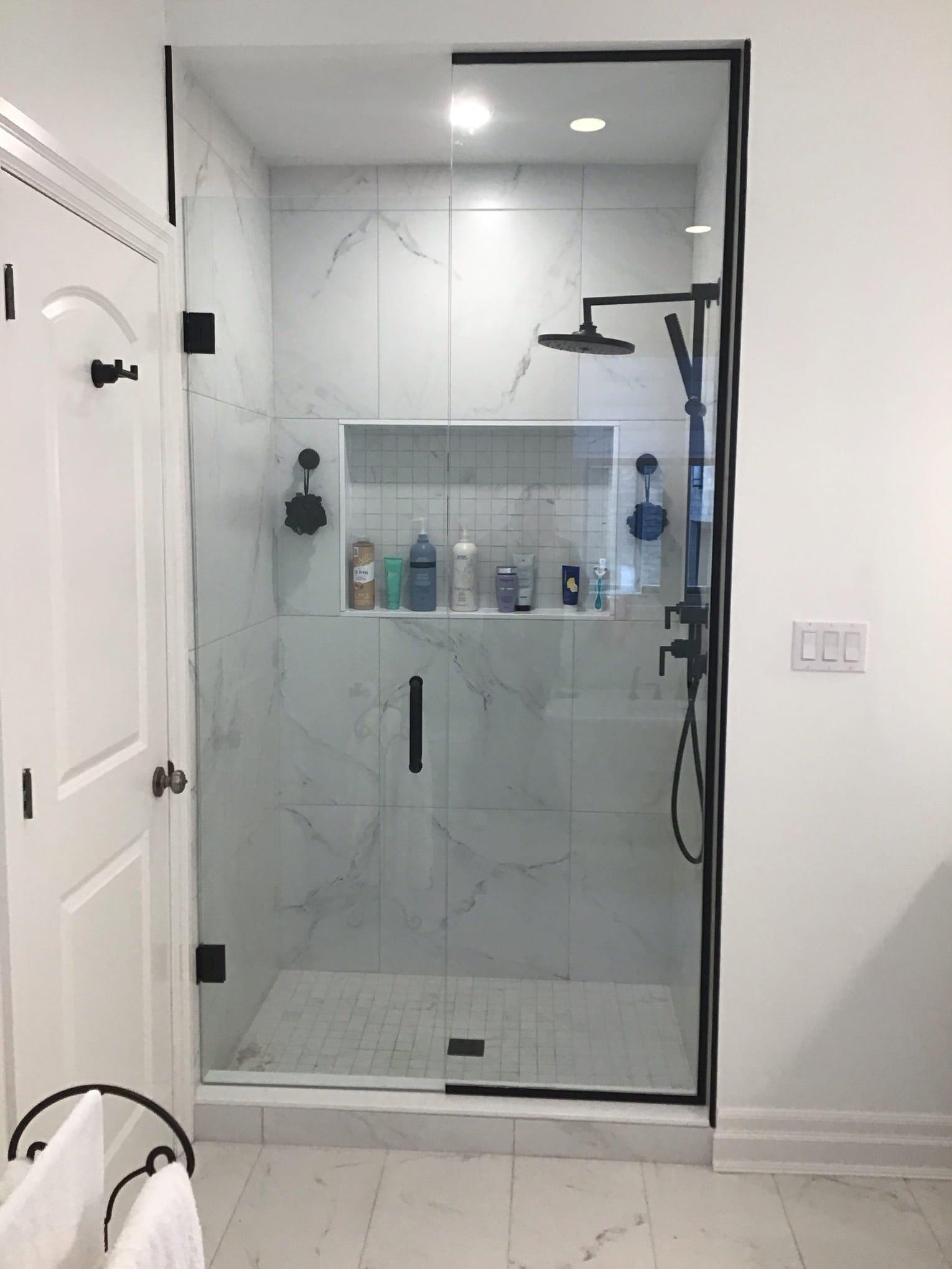 bathroom-renovation-london-ontario-donaldson.jpg Modern walk-in shower with black-framed glass, white marble-look tiles, black fixtures, and a filled niche.