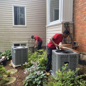 Two technicians installing air conditioning units