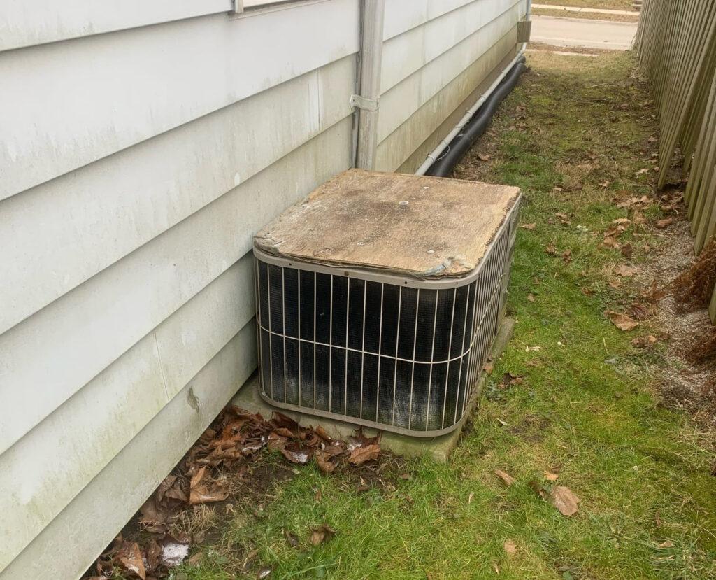 Aging AC unit looking broken and old.